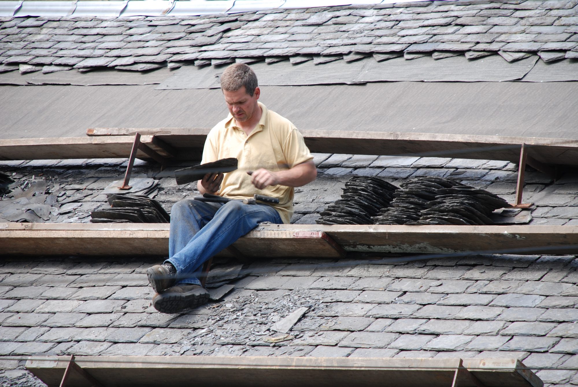 A time-served slater working slate onto a pitched roof